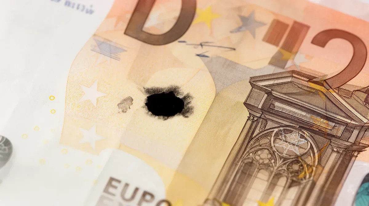Gros plan sur un billet de 20 euros avec une petite tache d'encre noire accidentelle, montrant les éléments de sécurité