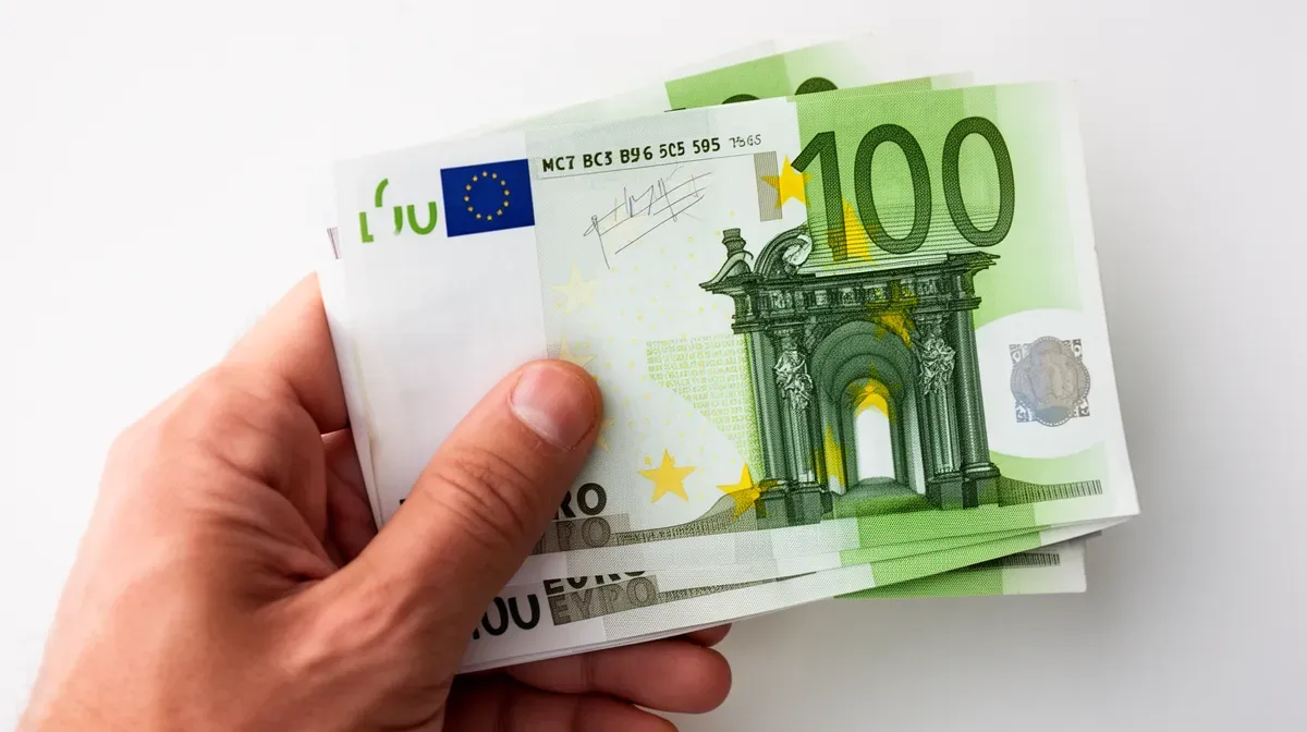 Main tenant des billets de banque en euros, symbole de la rémunération